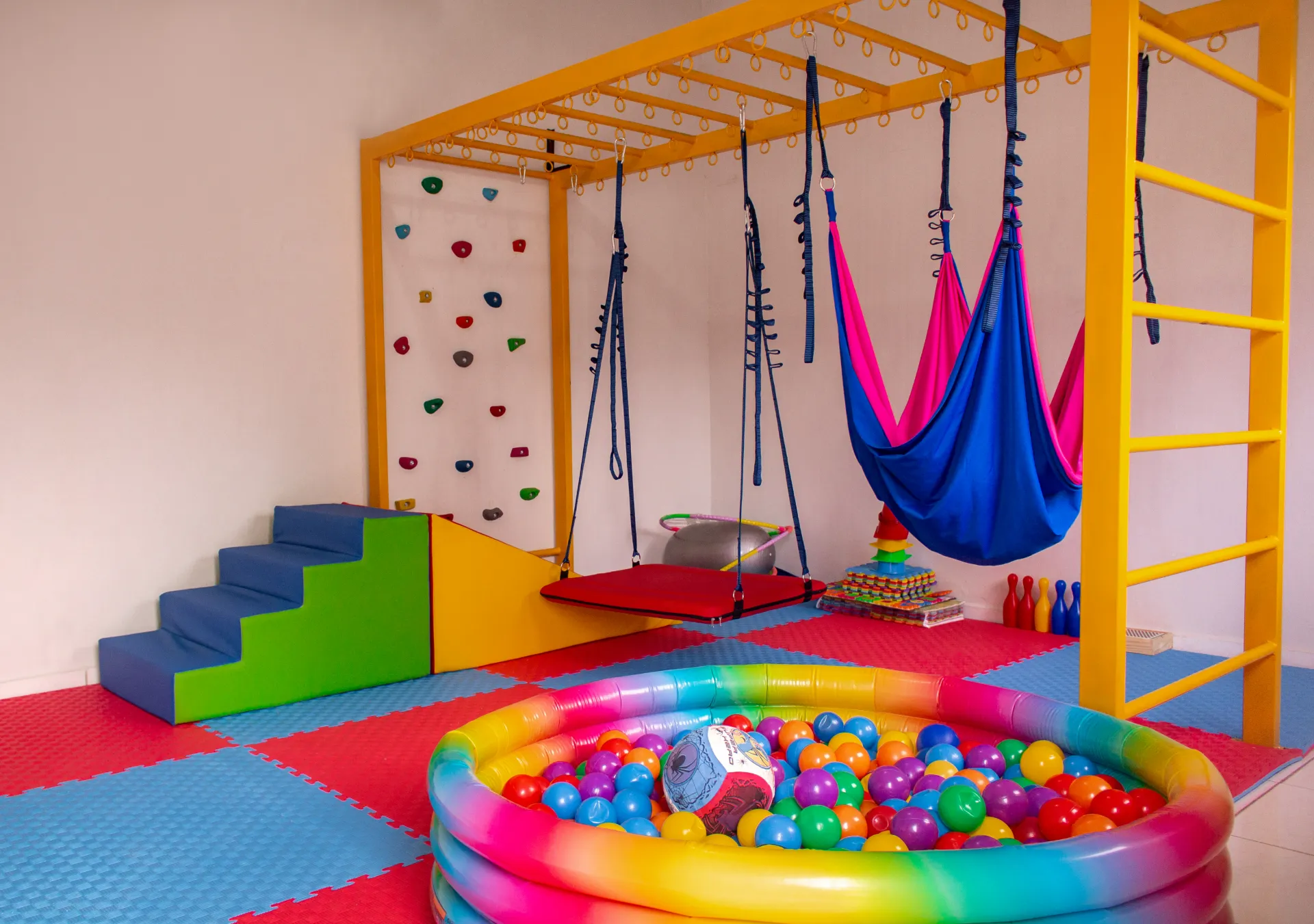 Sala de fisioterapia pediátrica com brinquedos e equipamentos sensoriais